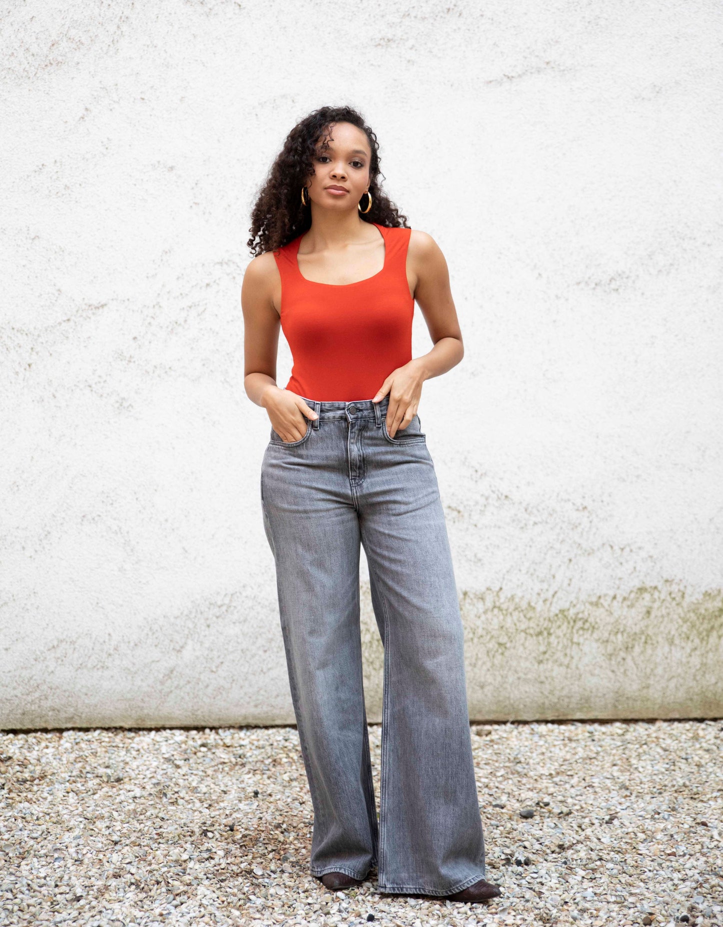 EMMI sweetheart-neck bodysuit styled with jeans and boots, front view, burnt red