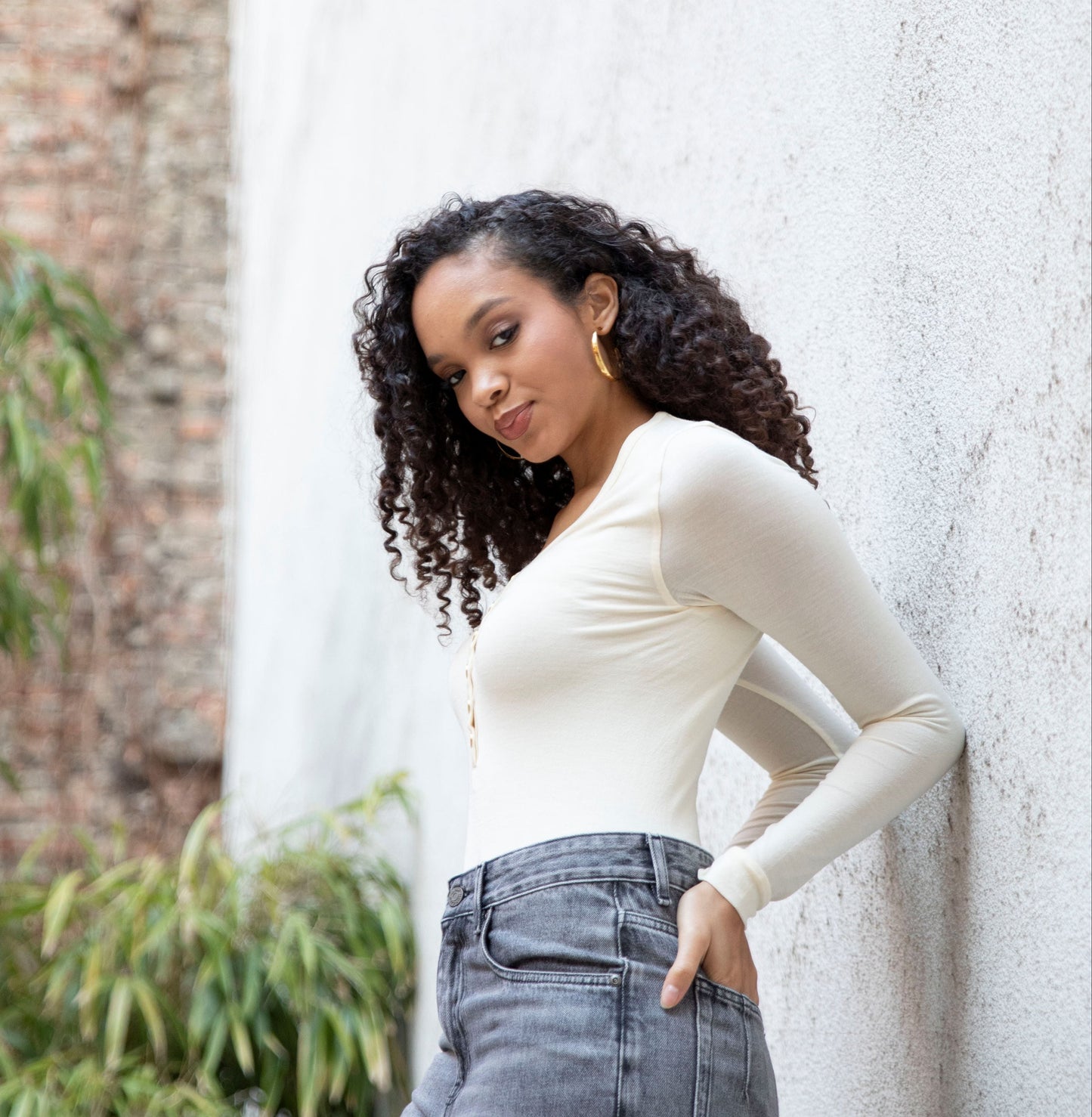 MARA V-neck bodysuit styled with jeans, side view showing seamless bodice, bright cream
